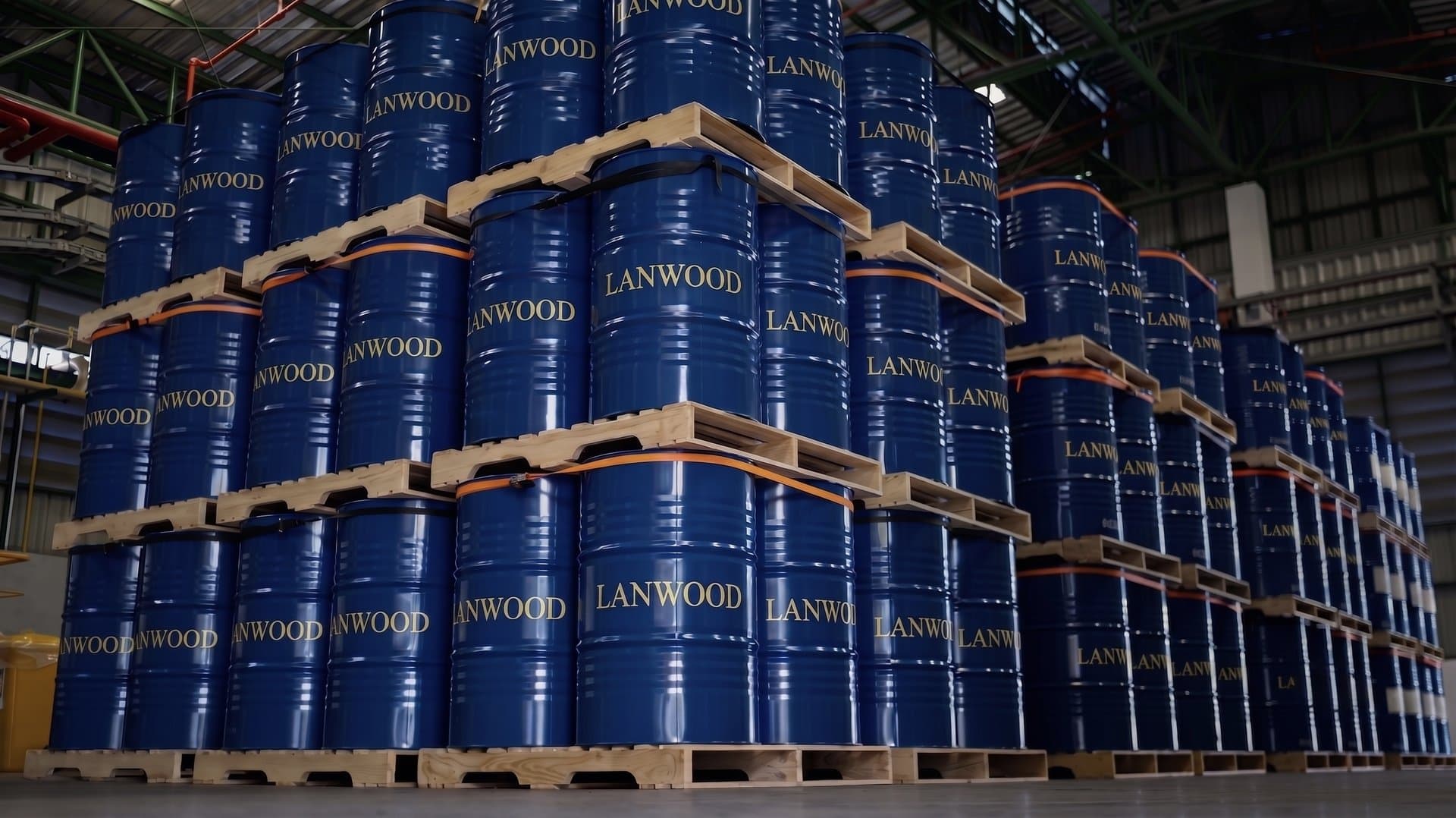 Stacked blue Lanwood-branded oil drums in a warehouse